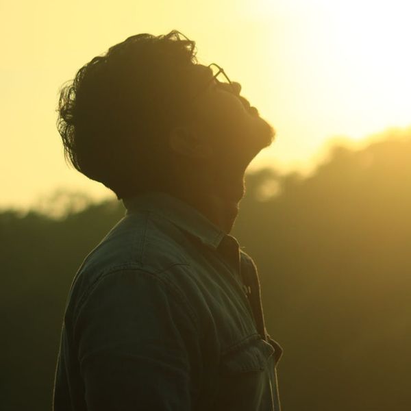 Side profile of a person meditating peacefully outdoors.